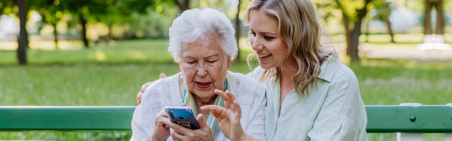 caregiver and elderly woman looking at the phone
