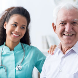 Laughing geriatric nurse sits at the bed of an elderly woman